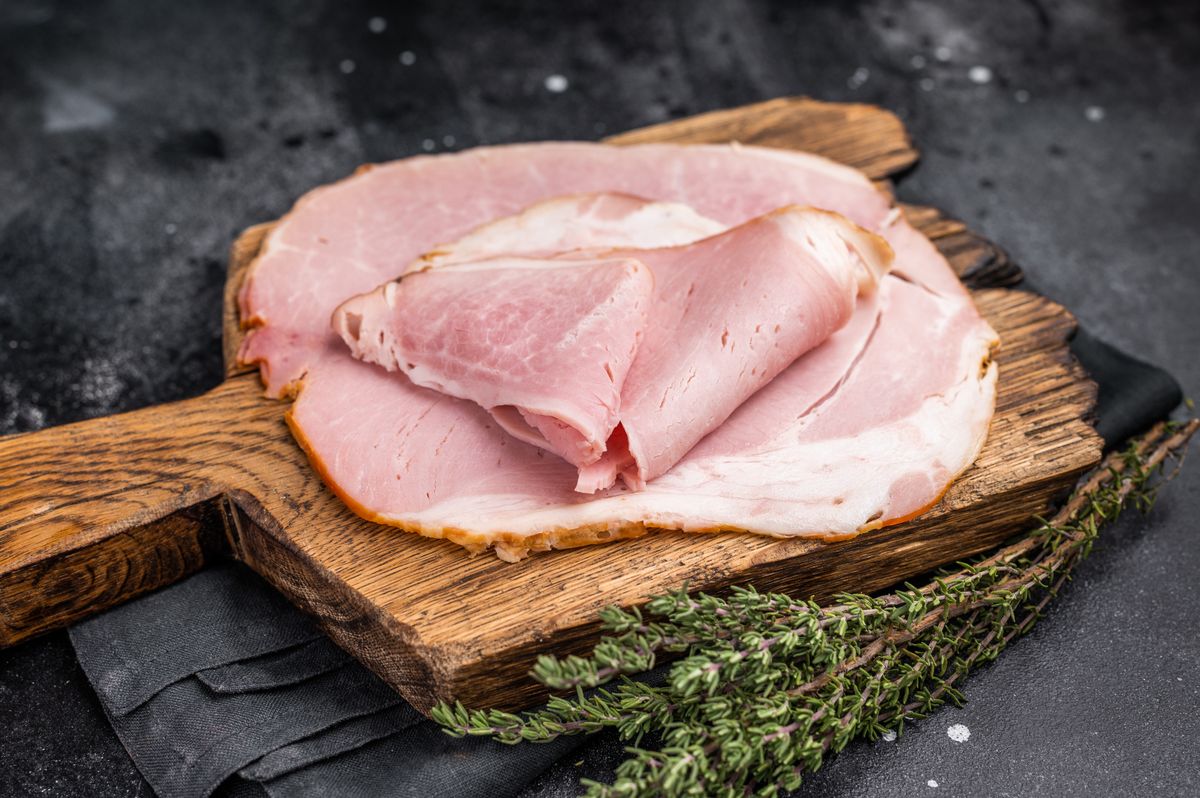 Geräucherter Schinken in Scheiben geschnitten auf rustikalem Holzbrett